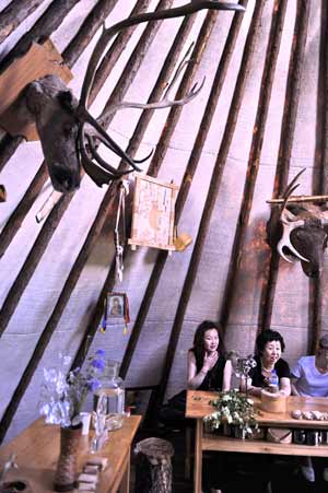 Visitors experience a bark house used to be home of Owenke ethnic group in Genhe City of north China's Inner Mongolia Autonomous Region, on Aug. 16, 2009.