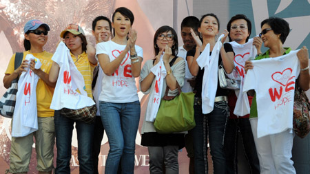 Pop singer Coco Lee (C) poses for photos with fans on a promotion event of her new album in Taipei, southeast China's Taiwan Province, August 23, 2009, during which she raises donations for the typhoon Morakot hit area in Taiwan by rummage sales of T-shirts designed by herself with a designing group.