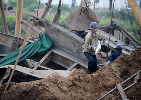 A worker removes debris at the gate of a pit where a blast of a coal mine took place in Heshun County, north China's Shanxi Province, August 25, 2009, as rescue works are continuing. Eleven people have been killed, three are missing and two survived following a gas blast in the Xingguang Coal Company Ltd. here at about 11:10 AM on Monday, the local authorities said.