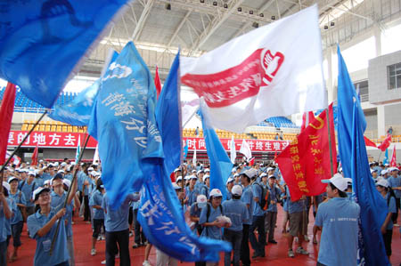 Postgraduate volunteers who are to set out on their obligation as assisting tutors wave their banners during the setting-off ceremony in Guiyang, southwest China's Guizhou Province, August 25, 2009. 