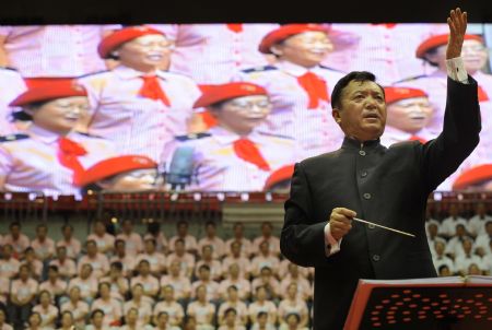 Local musician directs chorus during a celebration to greet the coming 60th anniversary of the founding of the People Republic of China in Urumqi, capital of northwest China's Xinjiang Uygur Autonomous Region on August 27, 2009. 