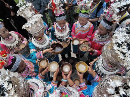 Girls pour wine for guests when celebrating the Chixin Festival, or New Grain Tasting Festival, in a village of the Miao ethnic group in Duyu City of southwest China's Guizhou Province, August 28, 2009.