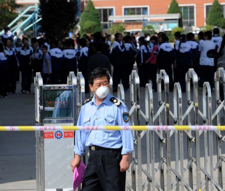 A health official guards at the entrance of a middle school in Lanzhou, capital of northwest China's Gansu Province, August 31, 2009. A/H1N1 flu cases broked out in the middle school there since August 28, and the confirmed infected patients grew to 26 till 3:00 PM August 30.