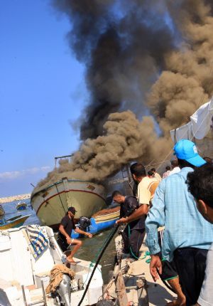 Palestinian fishermen try to put out fire on a boat after being hit by an Israeli shell at the Gaza city port, August 31, 2009. The Israeli navy set fire to a Palestinian fishing boat off Gaza shore Monday morning and a fisherman was injured, Palestinian sources and witnesses said.