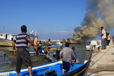 Palestinian fishermen try to put out fire on a boat at the Gaza city port after being hit by an Israeli shell, August 31, 2009. 