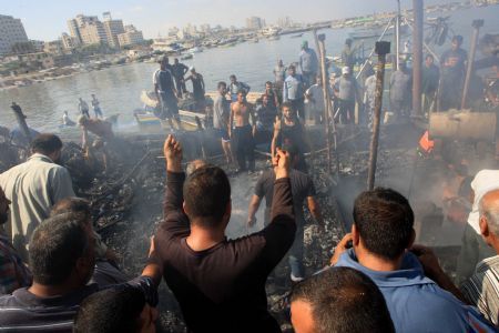 Palestinian fishermen try to put out fire on a boat at the Gaza city port after being hit by an Israeli shell, August 31, 2009.