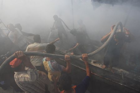 Palestinian fishermen try to put out fire on a boat at the Gaza city port after being hit by an Israeli shell, August 31, 2009. 