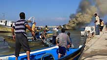 Palestinian fishermen try to put out fire on a boat at the Gaza city port after being hit by an Israeli shell, August 31, 2009.