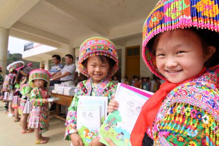 Girl student Wang Qiao (1st R) of a Hope School receives free school books in Longlin county, southwest China&apos;s Guangxi Zhuang Autonomous Region, August 31, 2009.(Xinhua/Lin Bin)