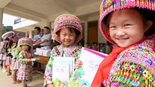 Girl student Wang Qiao (1st R) of a Hope School receives free school books in Longlin county, southwest China's Guangxi Zhuang Autonomous Region, August 31, 2009.