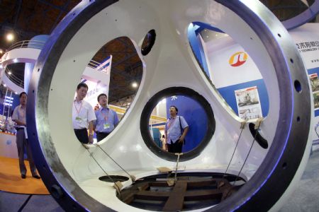 Visitors watch the wheel hub earmarked for the giant pneumatic power generating sets, at the 3-day-long 2009 China International Pneumatic, Solar and Nuclear Power Industry, concurrently Electric Power and Electrician Equipment and Technology Exposition, which is held at the China International Exhibition Center, drawing some 800 enterprises from both China and overseas, at Beijing, September 2, 2009.