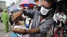 A street vendor helps a boy wear a protective mask in Dhaka, capital of Bangladesh, September 3, 2009. The total number of people infected by A/H1N1 flu in Bangladesh has so far reached 275, as 16 more new cases were detected on Thursday.