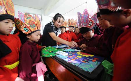 A teacher of the Naxi ethnic group teaches her students how to draw traditional paintings of Dongba culture at a primary school in Lijiang, southwest China&apos;s Yunnan Province, September 4, 2009. 