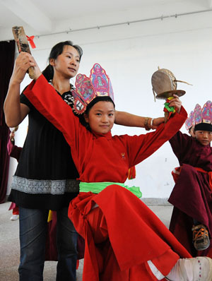A teacher of the Naxi ethnic group teaches a student to perform traditional dance of Dongba culture at a primary school in Lijiang, southwest China&apos;s Yunnan Province, September 4, 2009. 