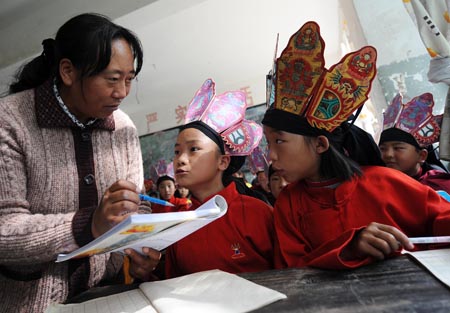 A teacher of the Naxi ethnic group teaches a student to perform traditional dance of Dongba culture at a primary school in Lijiang, southwest China&apos;s Yunnan Province, September 4, 2009. 