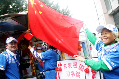 Volunteers hang up China's National Flag at the service station for the National Day celebrations on a street in Beijing, China, September 7, 2009.