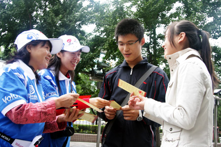 National Day celebration volunteers hand out brochures to tourists on a street in Beijing, China, September 7, 2009.