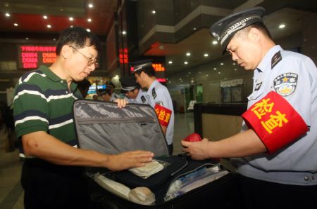 A policeman conducts security check on a passenger's hand luggage at the Hangzhou Railway Station, in east China's Zhejiang Province, September 8, 2009. A series of strict security measures have been taken as the 60th anniversary of the founding of the People's Republic of China approaches.