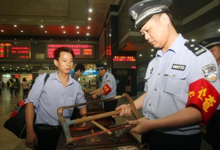 A policeman conducts security check on a passenger's hand luggage at the Hangzhou Railway Station, in east China's Zhejiang Province, September 8, 2009. 