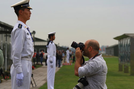 A foreign media staffer takes photos of a soldier at Beijing's Military Parade Village Thursday.[CFP]