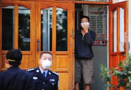 A masked student (R) stands at the entrance to Wing Building 8 of Zone B at Heilongjiang University in Harbin, capital of northeast China's Heilongjiang Province, September 14, 2009. 