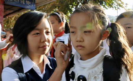 A teacher measures body temperature for a student at a primary school in Urumqi, capital of northwest China's Xinjiang Uygur Autonomous Region, on September 14, 2009. 