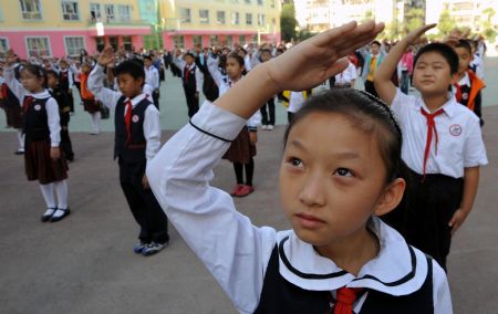 Students salute during a national flag raising ceremony at a primary school in Urumqi, capital of northwest China's Xinjiang Uygur Autonomous Region, on September 14, 2009.