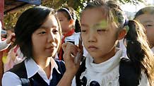 A teacher measures body temperature for a student at a primary school in Urumqi, capital of northwest China's Xinjiang Uygur Autonomous Region, on September 14, 2009.