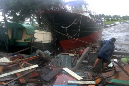 A person clears away the wreckage at the site where a vessel collided onto the bank as an aftermath of the gales and heavy rains brought by the tropical storm Koppu inside Xiangzhou Fishery Harbour, Zhuhai City, south China's Guangdong Province, September 15, 2009.