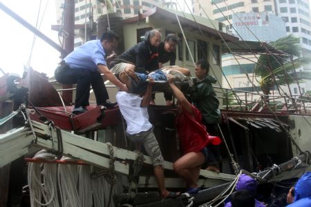 Rescuers help an injured sailor off a vessel which collided onto the bank as an aftermath of the gales and heavy rains brought by the tropical storm Koppu inside Xiangzhou Fishery Harbour, Zhuhai City, south China's Guangdong Province, September 15, 2009. 