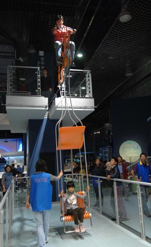 Visitors experience an air bicycle in the new China Science and Technology Museum in Beijing, capital of China, September 20, 2009. The Hi-tech and newly-built museum covering an area of 48,000 square meters was opened to the public on Sunday. 