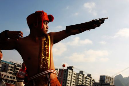 A younster shows his stunt of shooting crossbow to mark the forthcoming grand celebration of the 60th anniversary of the founding of the People's Republic of China, at Hechi City, southwest China's Guangxi Zhuang Autonomous Region, September 19, 2009.