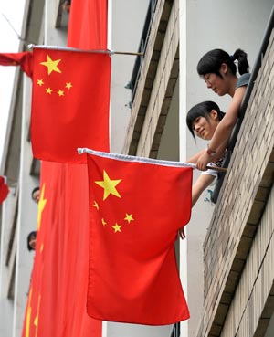 Two students hang the national flag on the balcony of their dormitory in Zhejiang University of Technology in Hangzhou, capital of east China's Zhejiang Province, on September 20, 2009