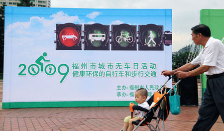People walk past a poster advocating the idea of the Car-Free Day in Fuzhou, capital of southeast China's Fujian Province, on September 22, 2009