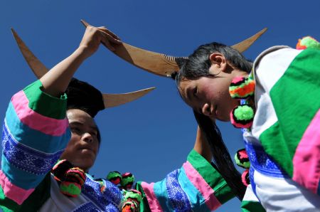 Men of the Miao ethnic group arrange decorations for each other before they perform at a leek flower cultural festival held in Hezhang, southwest China's Guizhou Province, September 22, 2009. The festival opened on Tuesday in Hezhang county that grows wild leek plants of more than 30 square kilometers. 