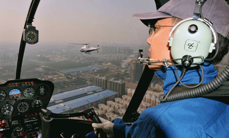 An aviation policeman pilots the police helicopter in a routine patrol aviation for the tightening the orderly security guarding for the grand celebration of the National Day, in Zhengzhou, central China's Henan Province, September 23, 2009.