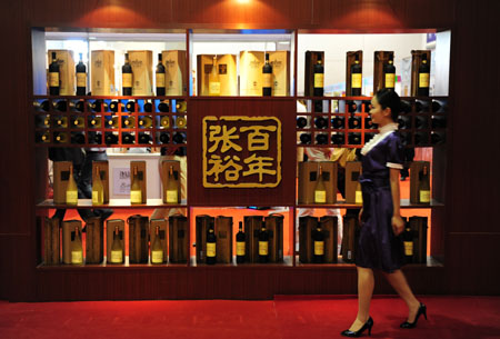 A young woman passes by an elaborate wine display rack during the 3rd Yantai International Wine Festival, which is set to feature series of activities including tasting and appreciating quality wine, grape-picking, fancy bartend concoction, etc, opening in Yantai, east China's Shandong Province, September 23, 2009.