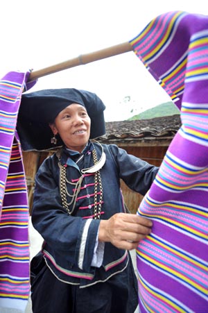 An old woman of Dark Cloth Zhuang dries cloth woven by herself in Napo county, southwest China's Guangxi Zhuang Autonomous Region, September 23, 2009.