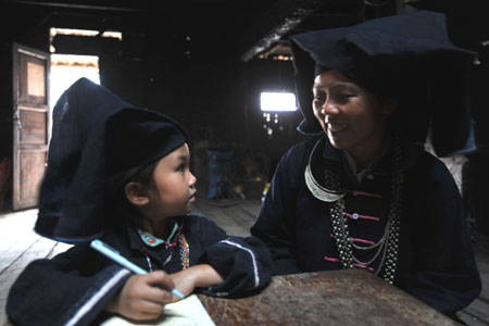 A woman of Dark Cloth Zhuang helps her daughter do homework in Napo county, southwest China's Guangxi Zhuang Autonomous Region, September 23, 2009.