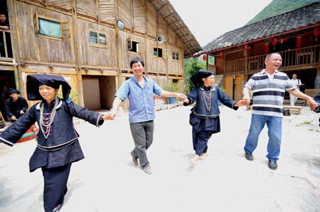 Women of Dark Cloth Zhuang dance with tourists in Napo county, southwest China's Guangxi Zhuang Autonomous Region, September 23, 2009.