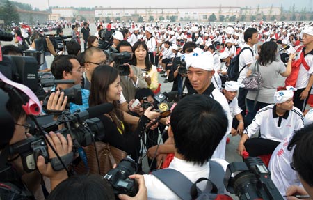 Journalsits interview a member of waist drum dance team from Ansai County of northwest China's Shaanxi Province during their rehearsal for the upcoming National Day massive celebration, in Beijing, September 25, 2009.