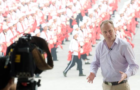 A reporter with BBC reports in front of waist drum dance team from Ansai County of northwest China's Shaanxi Province during their rehearsal for the upcoming National Day massive celebration, in Beijing, September 25, 2009.