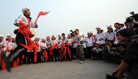 Cameramen shoot a member of waist drum dance team from Ansai County of northwest China's Shaanxi Province performing during their rehearsal for the upcoming National Day massive celebration, in Beijing, September 25, 2009. 