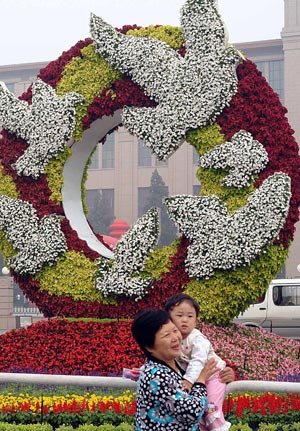 People pose for photos in front of a mosaiculture design in Beijing, capital of China, September 25, 2009.