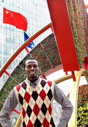 An overseas student poses for photos in front of a mosaiculture design in Beijing, capital of China, September 25, 2009.