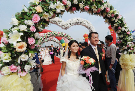 A groom walks with his bride during a mass wedding in Qingdao, east China&apos;s Shandong Province, September 27, 2009. The mass wedding, under the theme of &apos;blessing the homeland&apos;, was attended by 60 couples. The 60th anniversary of the founding of the People&apos;s Republic of China will be celebrated on October 1. 