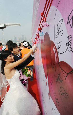 A couple hangs a &apos;heart lock&apos; during a mass wedding in Qingdao, east China&apos;s Shandong Province, September 27, 2009. The mass wedding, under the theme of &apos;blessing the homeland&apos;, was attended by 60 couples. The 60th anniversary of the founding of the People&apos;s Republic of China will be celebrated on October 1.