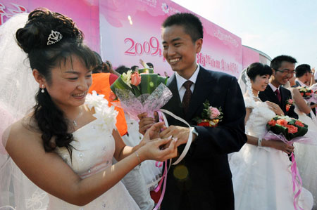 A couple exchanges the rings during a mass wedding in Qingdao, east China&apos;s Shandong Province, September 27, 2009. The mass wedding, under the theme of &apos;blessing the homeland&apos;, was attended by 60 couples. The 60th anniversary of the founding of the People&apos;s Republic of China will be celebrated on October 1.