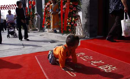 A small child plays games on Qianmen Street, one of Beijing's oldest commercial areas, in Beijing, capital of China, September 28, 2009.