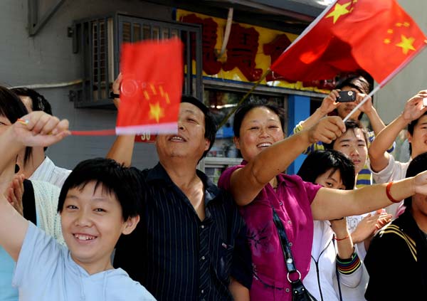 Local residents wave national flags when watching a parade of the celebrations for the 60th anniversary of the founding of the People&apos;s Republic of China, on Chang&apos;an Street in central Beijing, capital of China, October 1, 2009.